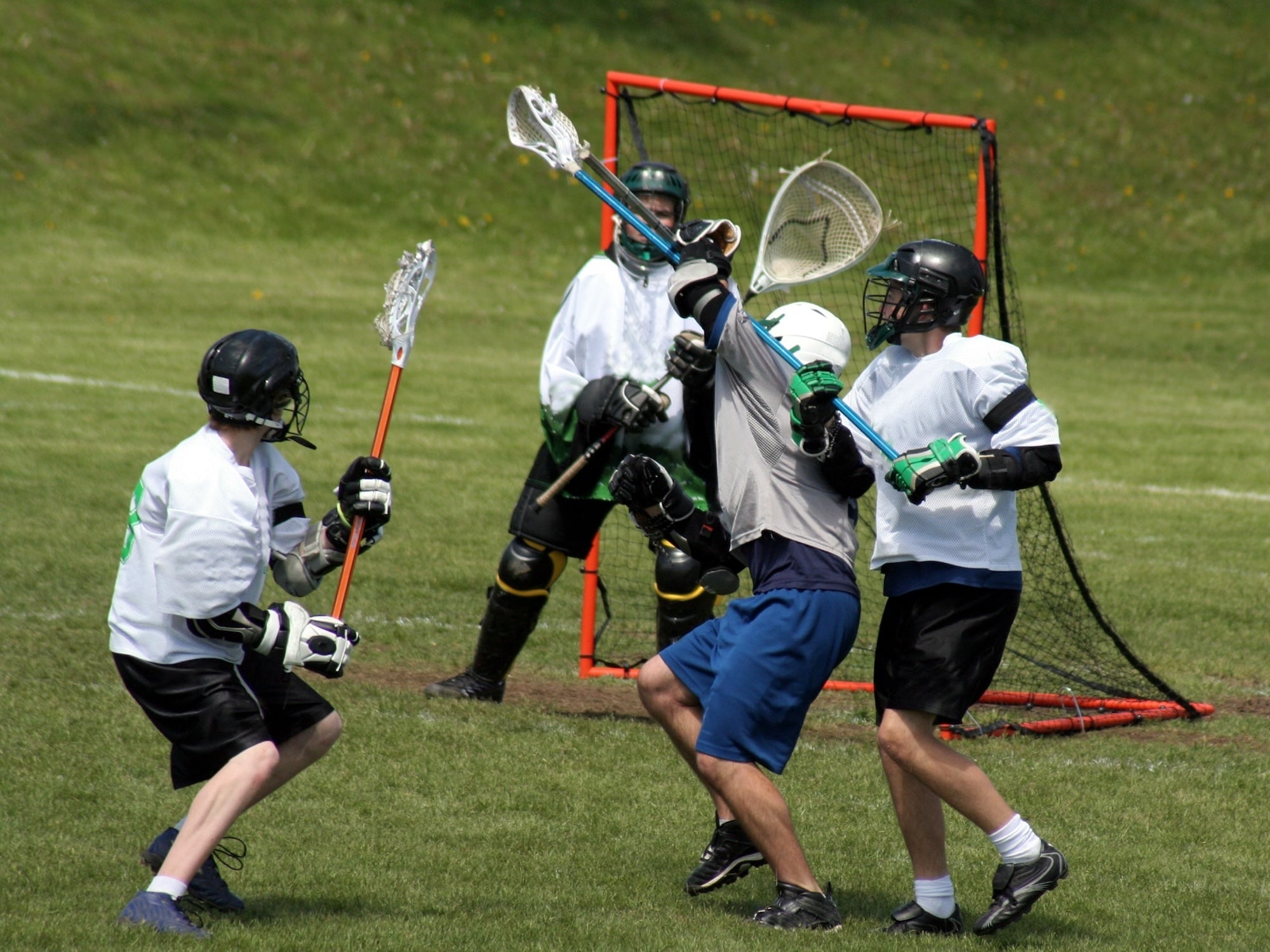 Lacrosse game in progress with players on a grass field