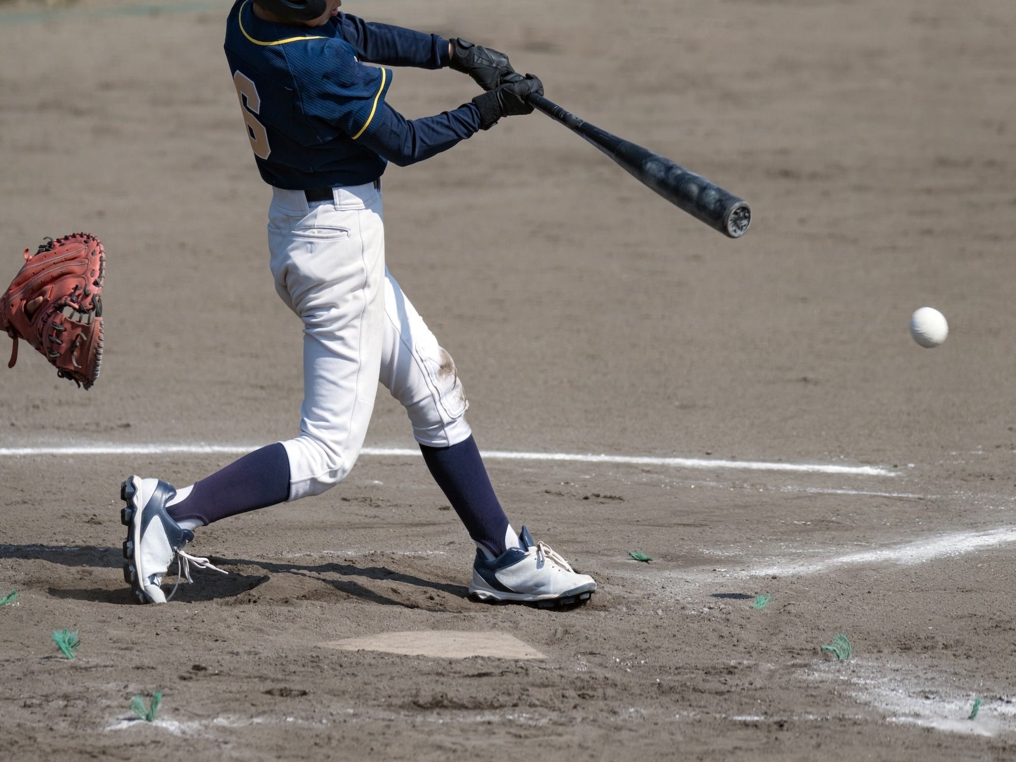 Baseball player in action on a dirt field with a ball and bat.