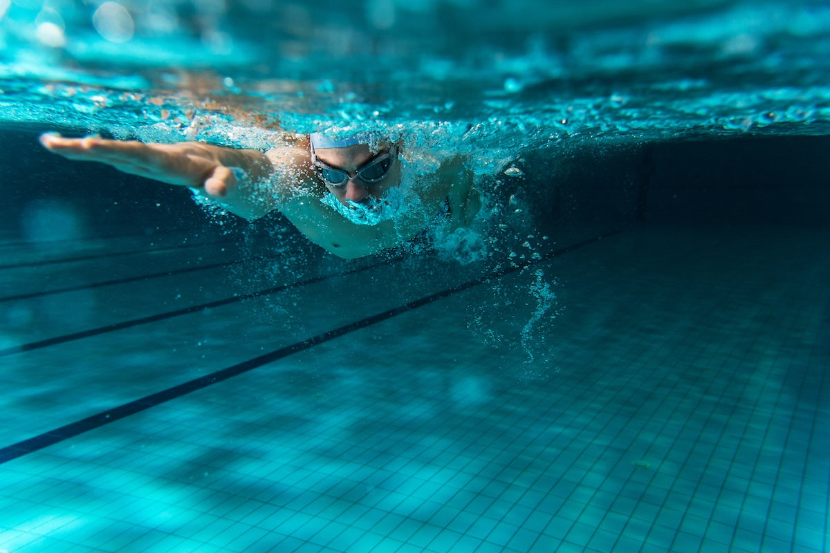 Person swimming underwater in a pool