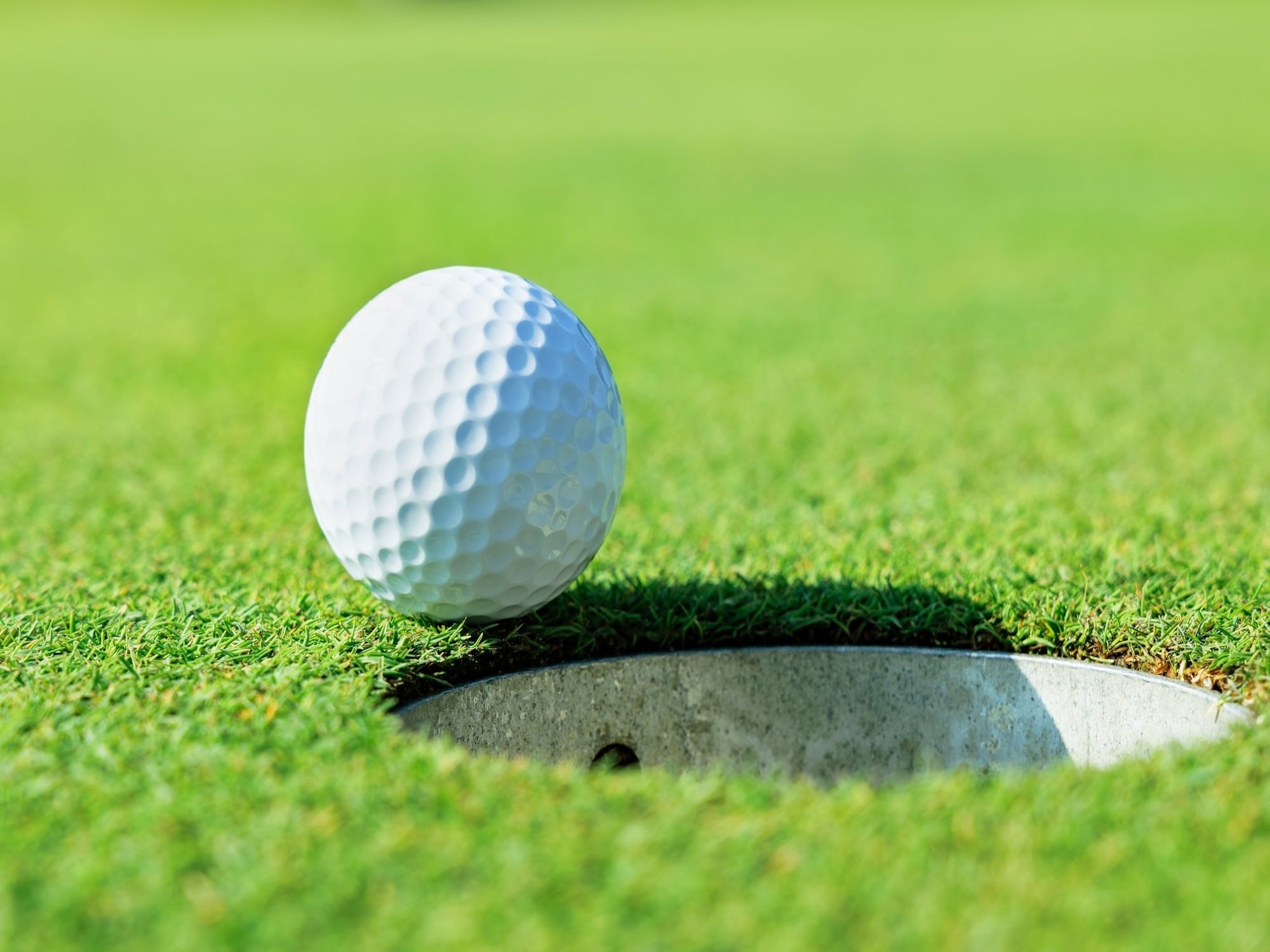 Golf ball near a hole on a green golf course